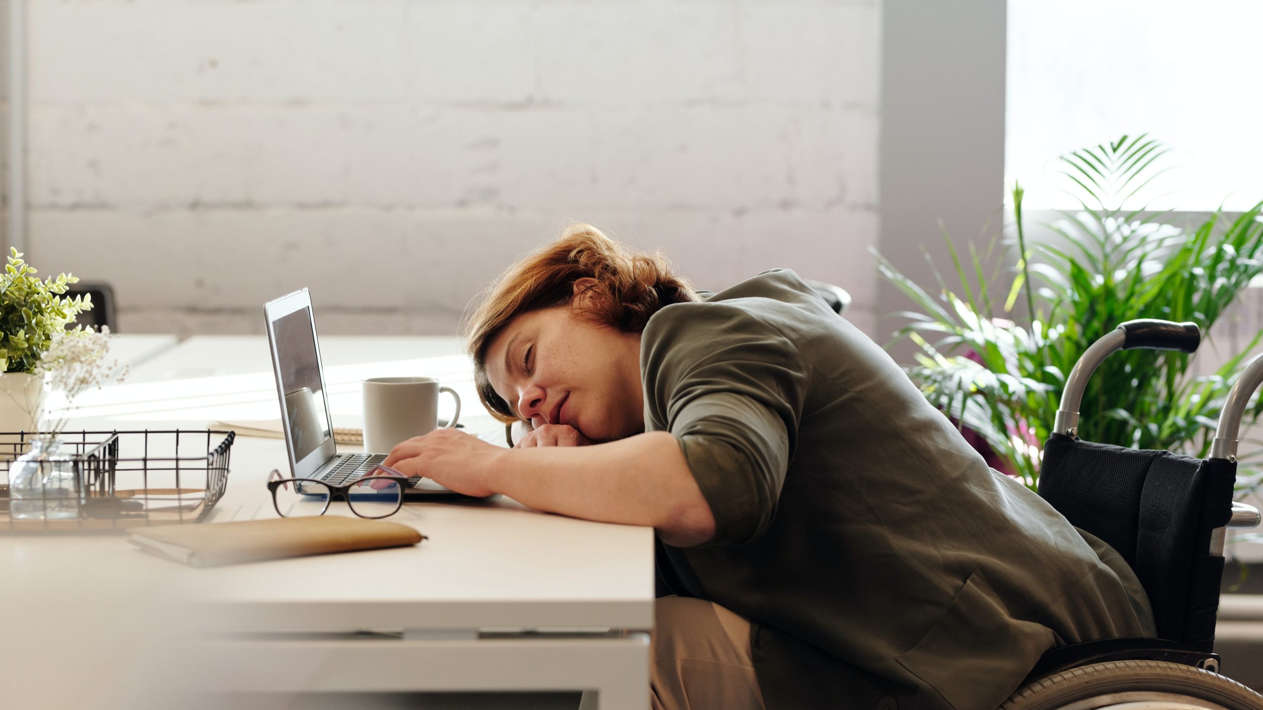 Woman with hormonal dysfunction leaning on her desk feeling drowsy. sleepy and tired.